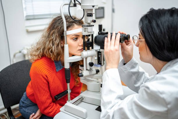 Ophthalmologist performing eye exam with optical equipment on female patient Ophthalmologist performing eye exam with optical equipment on female patient